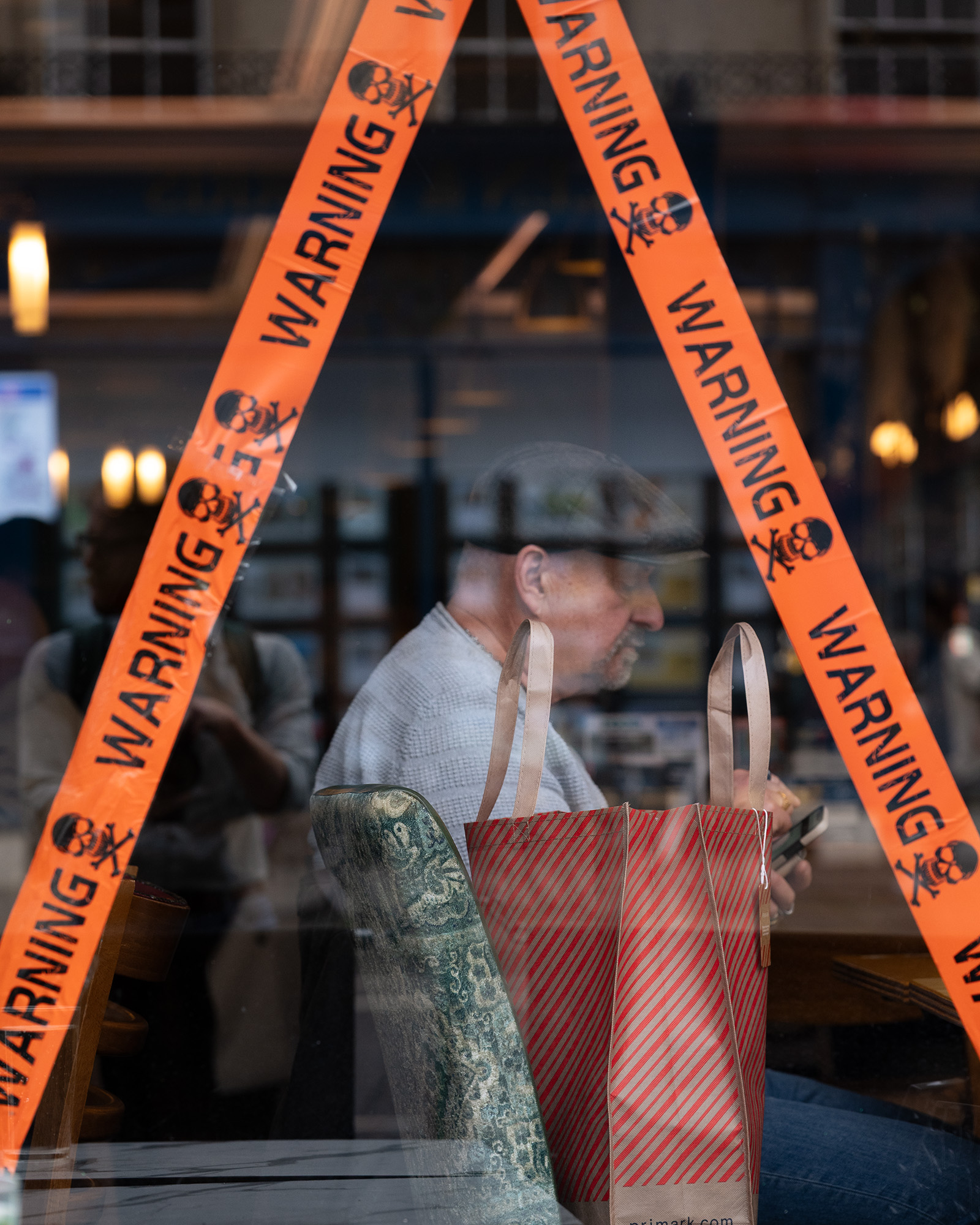 Photograph of man in restaurant with 'WARNING' tape on the window
