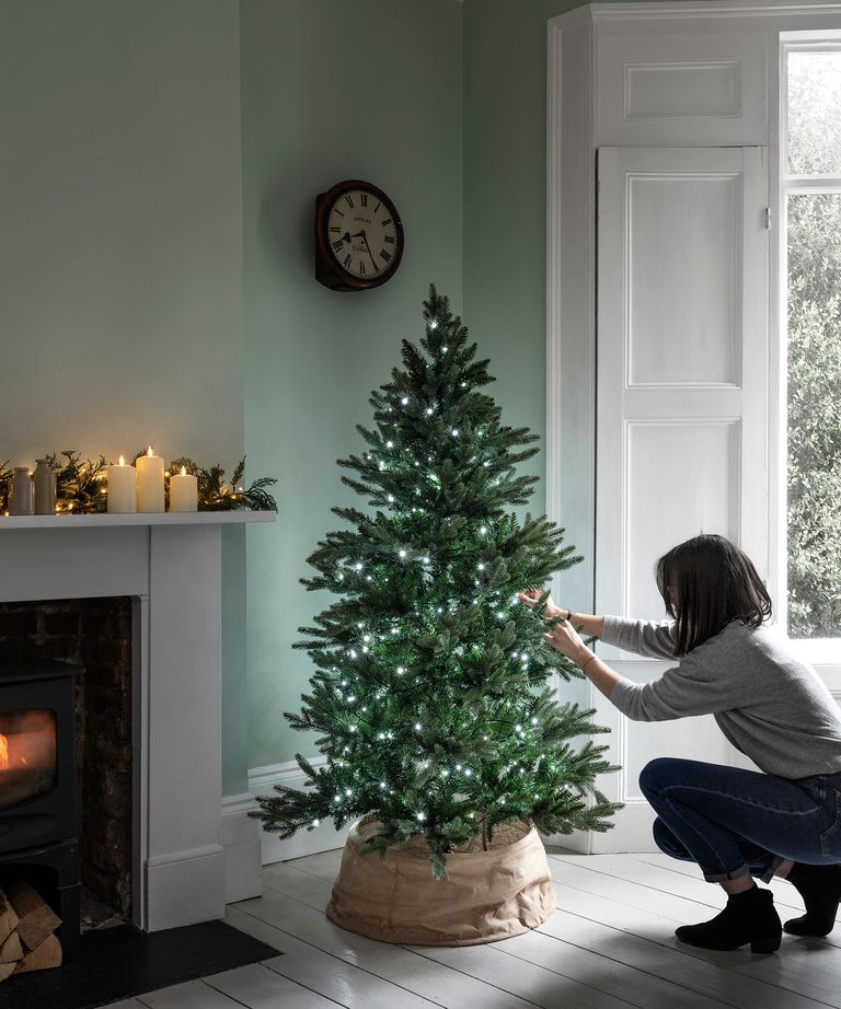 Woman putting lights on a Christmas tree, Lights4fun