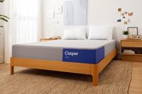 Image shows the Casper One mattress on a light wooden bed frame placed on a jute rug