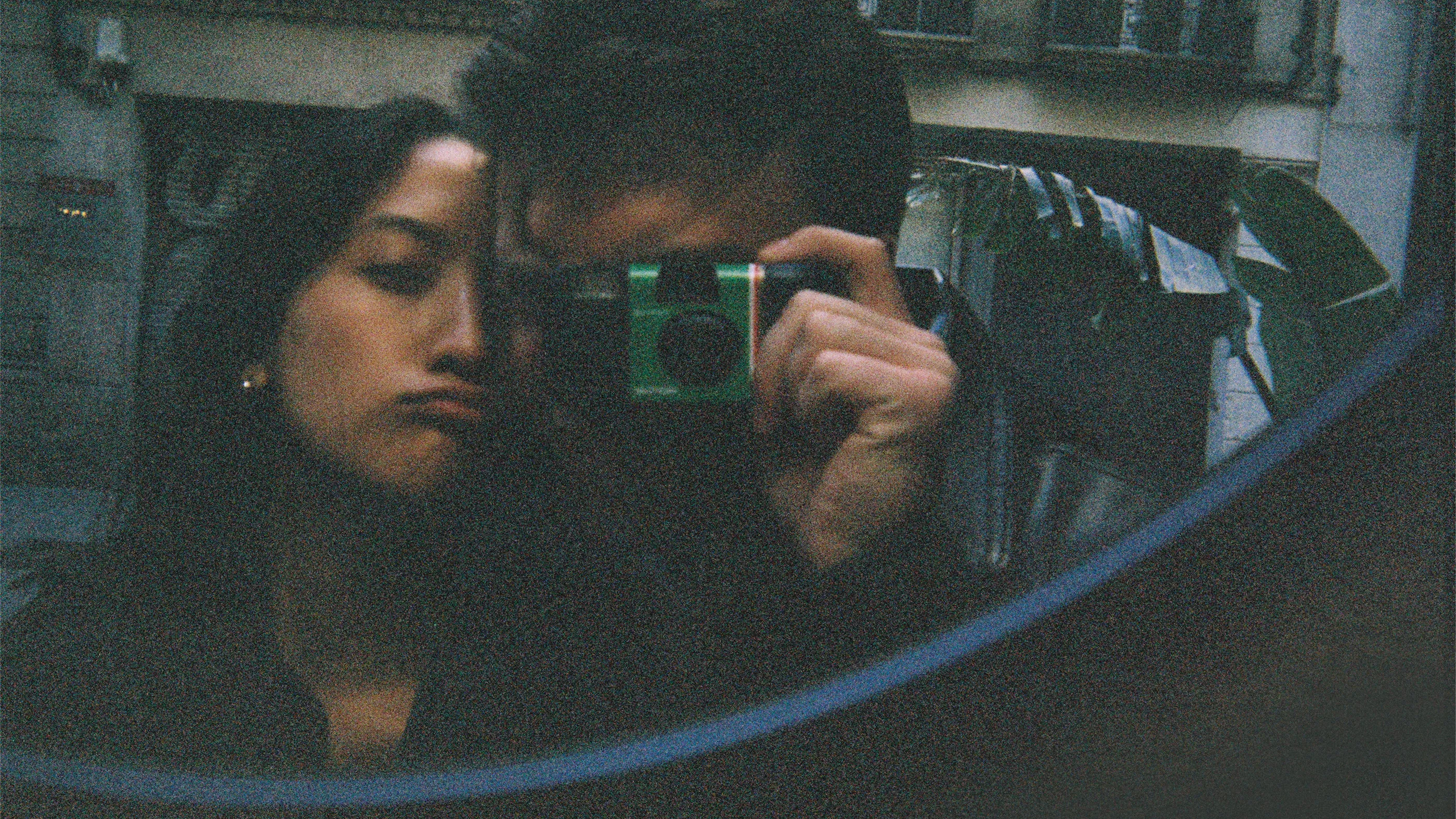 A person takes a selfie in the mirror with a Fujifilm Quicksnap disposable film camera