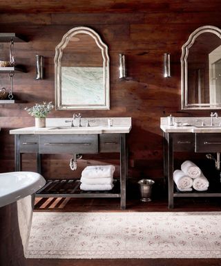 bathroom with custom iron vanities, dark wood walls and floor and patterned rug