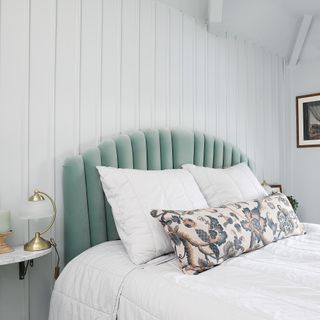 White bedroom with panelled wall and velvet scalloped headboard