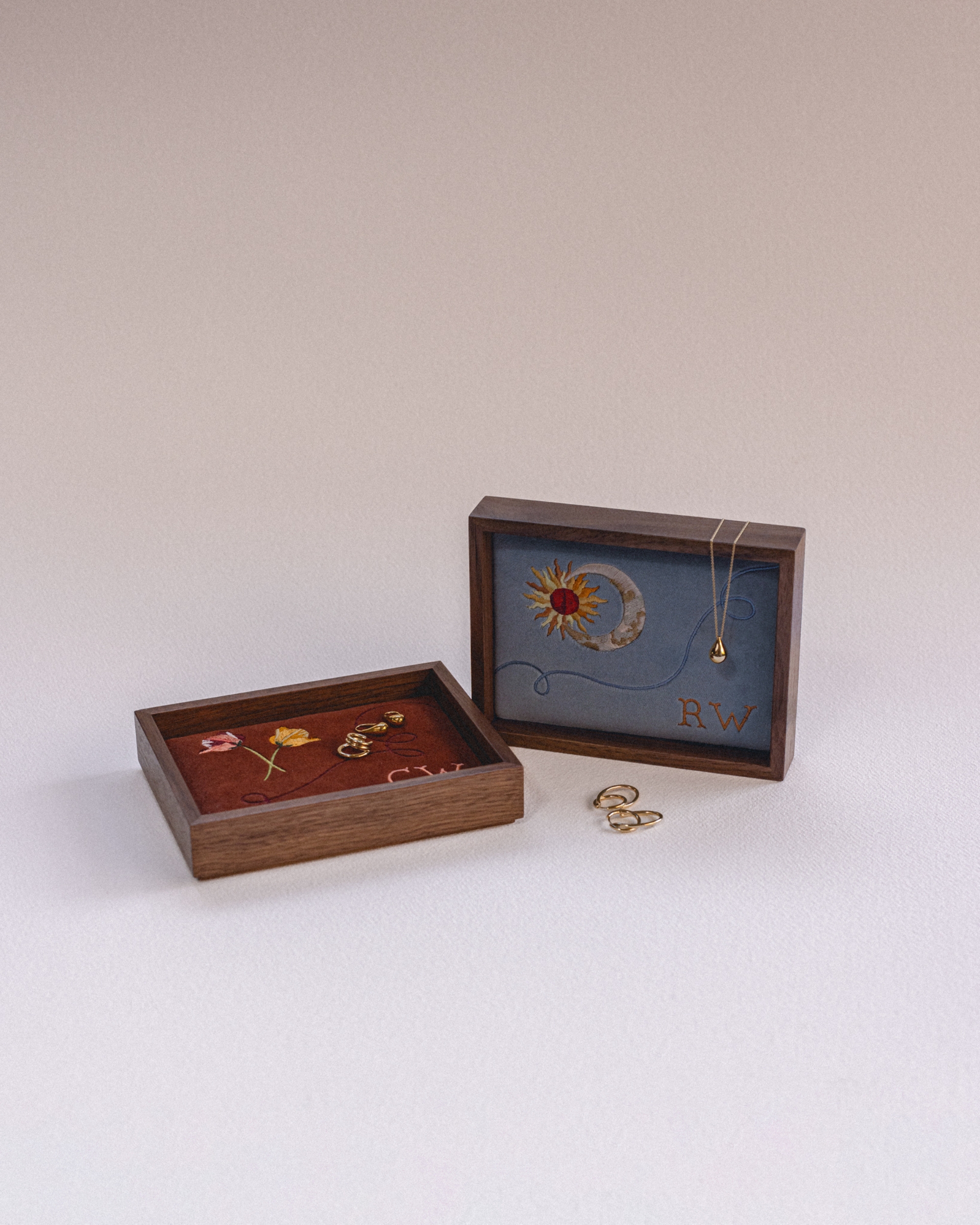 Image of two wooden jewelry boxes with a velvet background and embroidered with imagery.