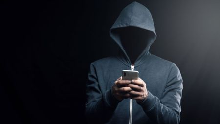A dark figure in a hoodie representing a hacker.