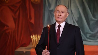 Russian President Vladimir Putin holds a candle in church