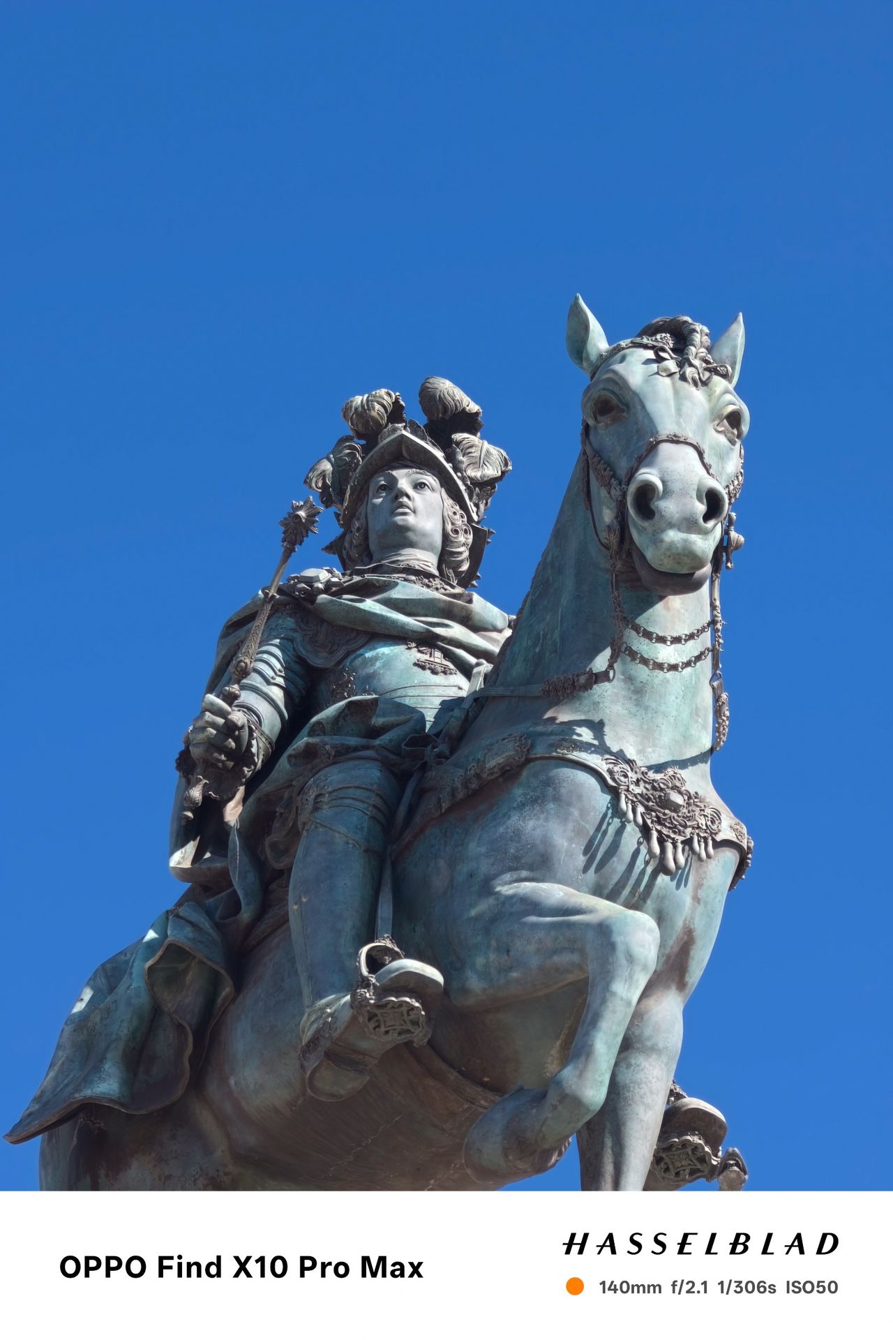 Low-angle close-up of a bronze equestrian statue against a clear blue sky.