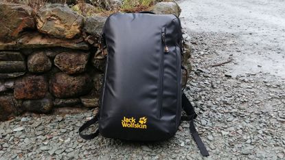 Jack Wolfskin Expedition Pack 42 on shingled ground, against a stone wall