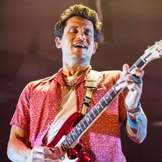 John Mayer playing an electric guitar during a stage performance