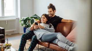 What network is Mint Mobile on? Couple look at cell phone while sat on sofa together
