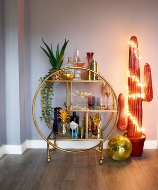 Brass drinks trolley with fun Christmas cactus wrapped in fairy lights