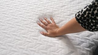 A hand pressing into white surface of Nectar Classic memory foam mattress