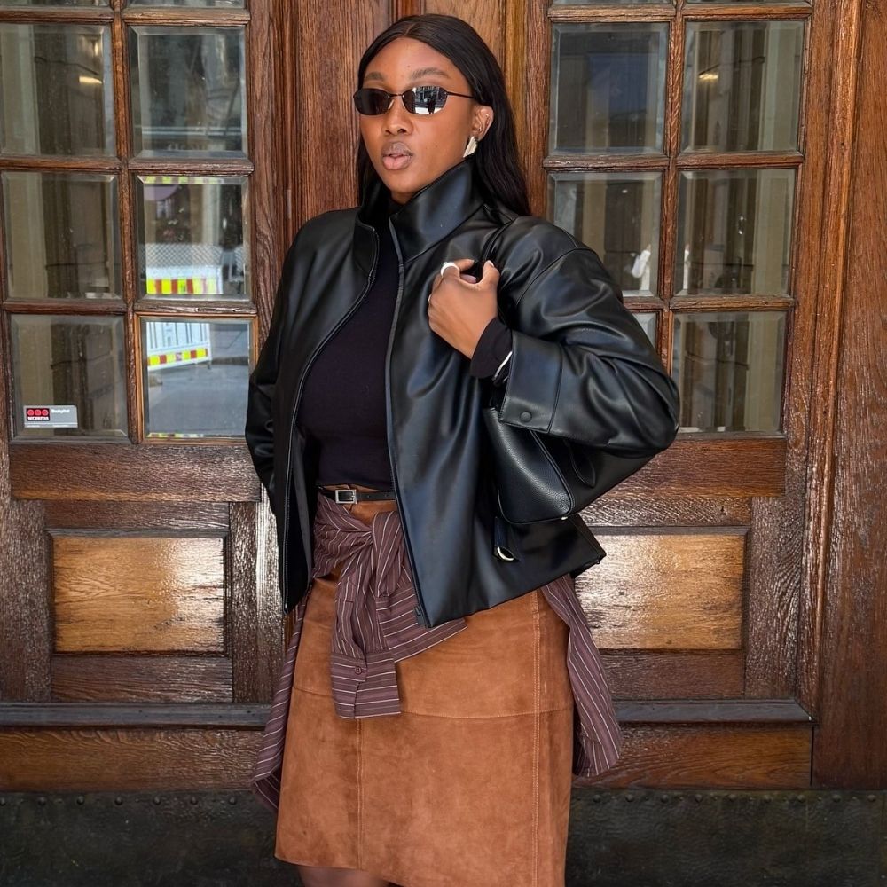 Influencer @nnennaechem wears a brown suede skirt with a black leather jacket and black flip-flops.