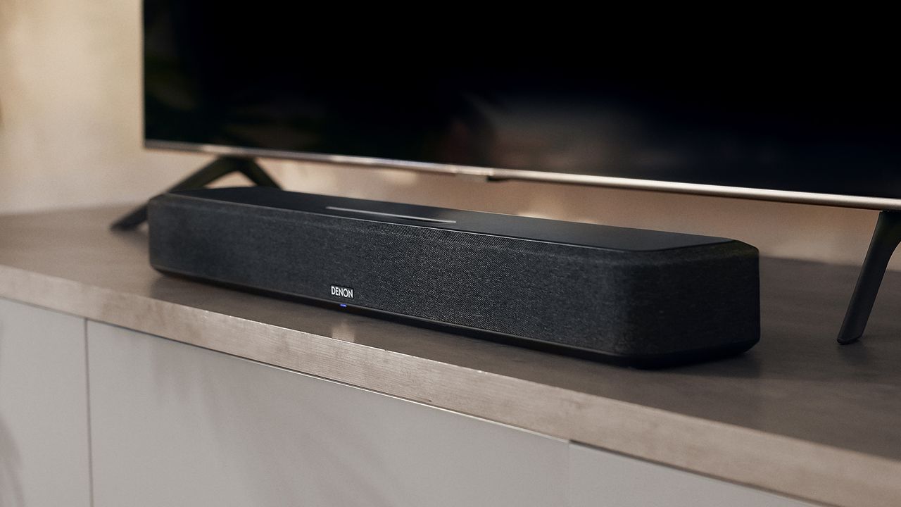 Denon Home Sound Bar 550 in front of TV on wooden surface