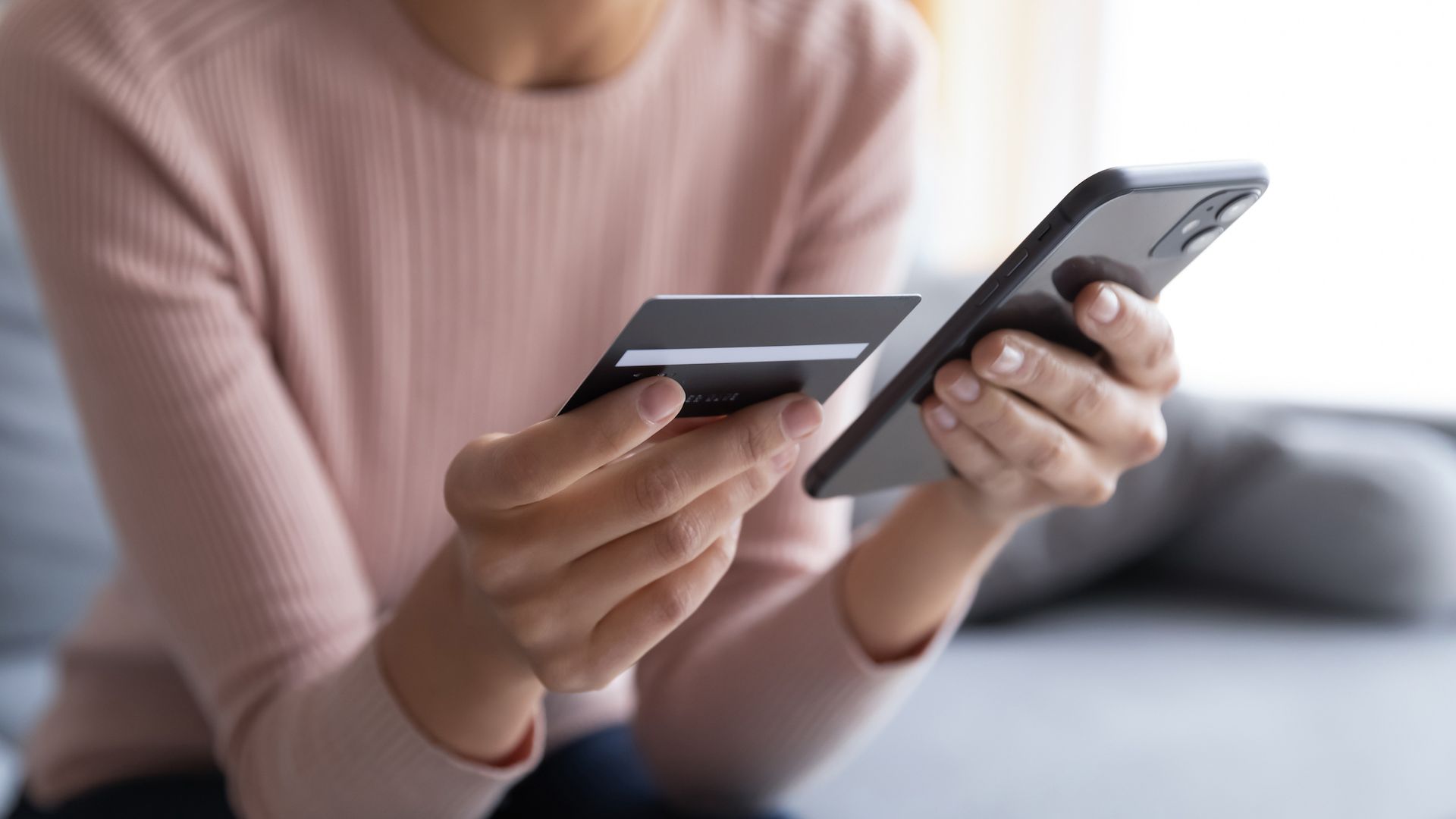 Person holding a credit card in one hand and a phone in the other