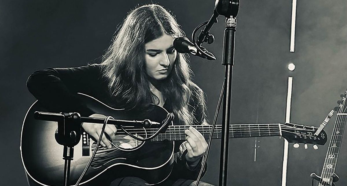 A portrait of Muireann Bradley playing her Waterloo acoustic guitar