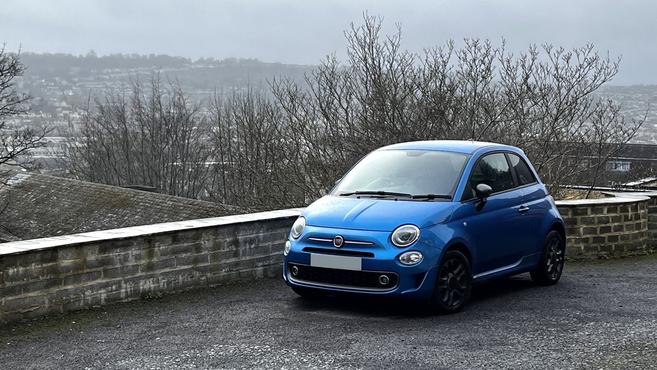 A blue Fiat 500 overlooking a city