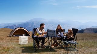 A family camping on a hill with a portable Bluetti power station