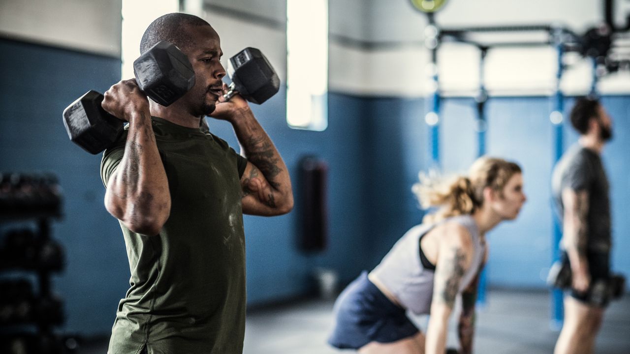 Man holding hex dumbbells by shoulders in the gym