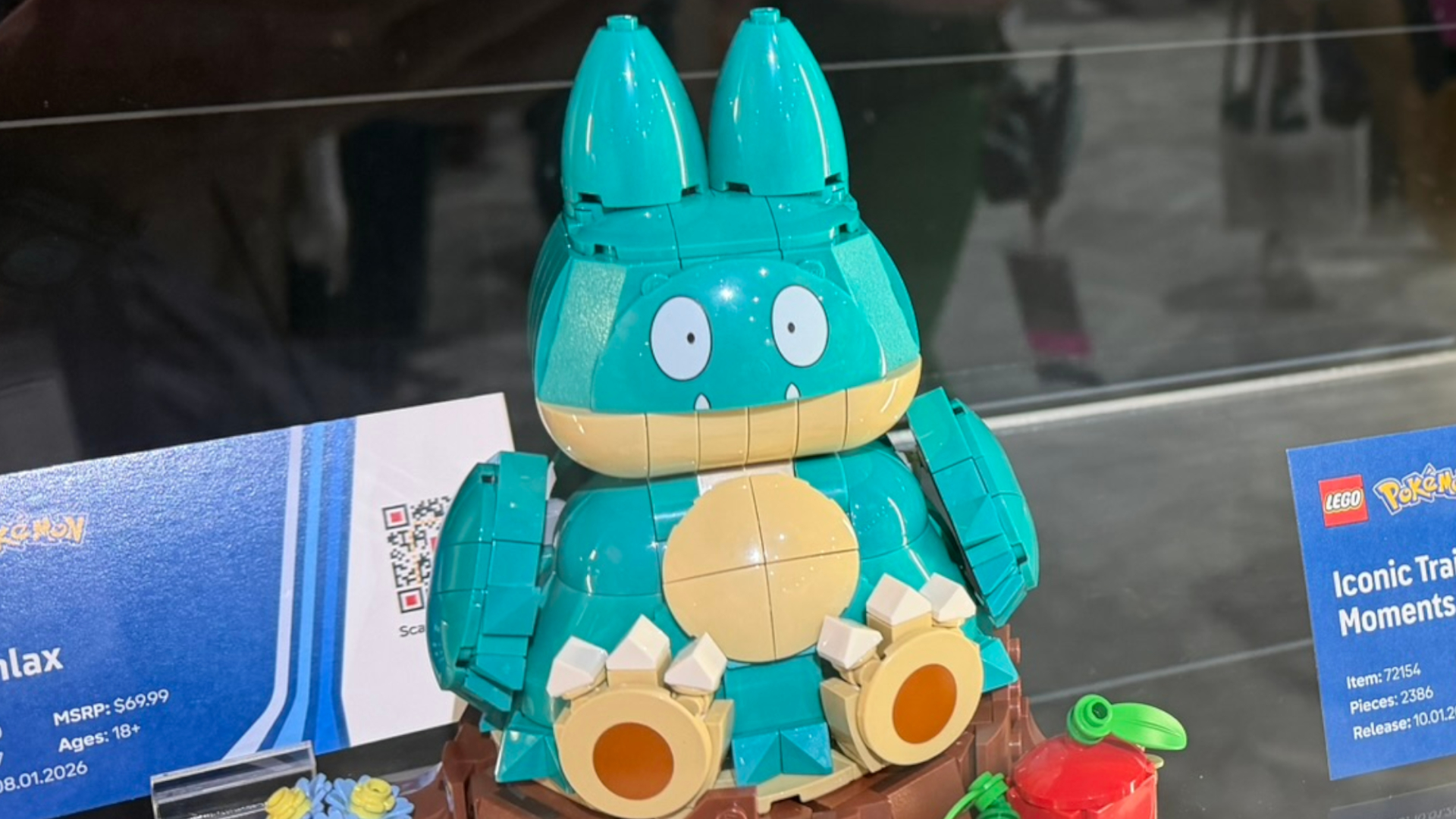 A Munchlax Lego set in a cabinet, with information plaques behind and to the side of it