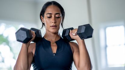 Woman holding a pair of dumbbells at her shoulders