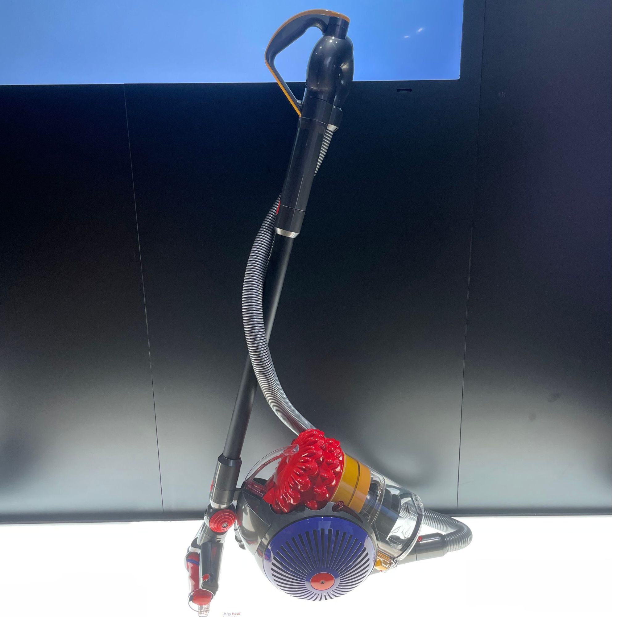Dyson Big Ball Konical corded vacuum cleaner on a white stand with a black background behind it