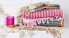 Towel stack featuring colorful, multi striped designs with fringing.