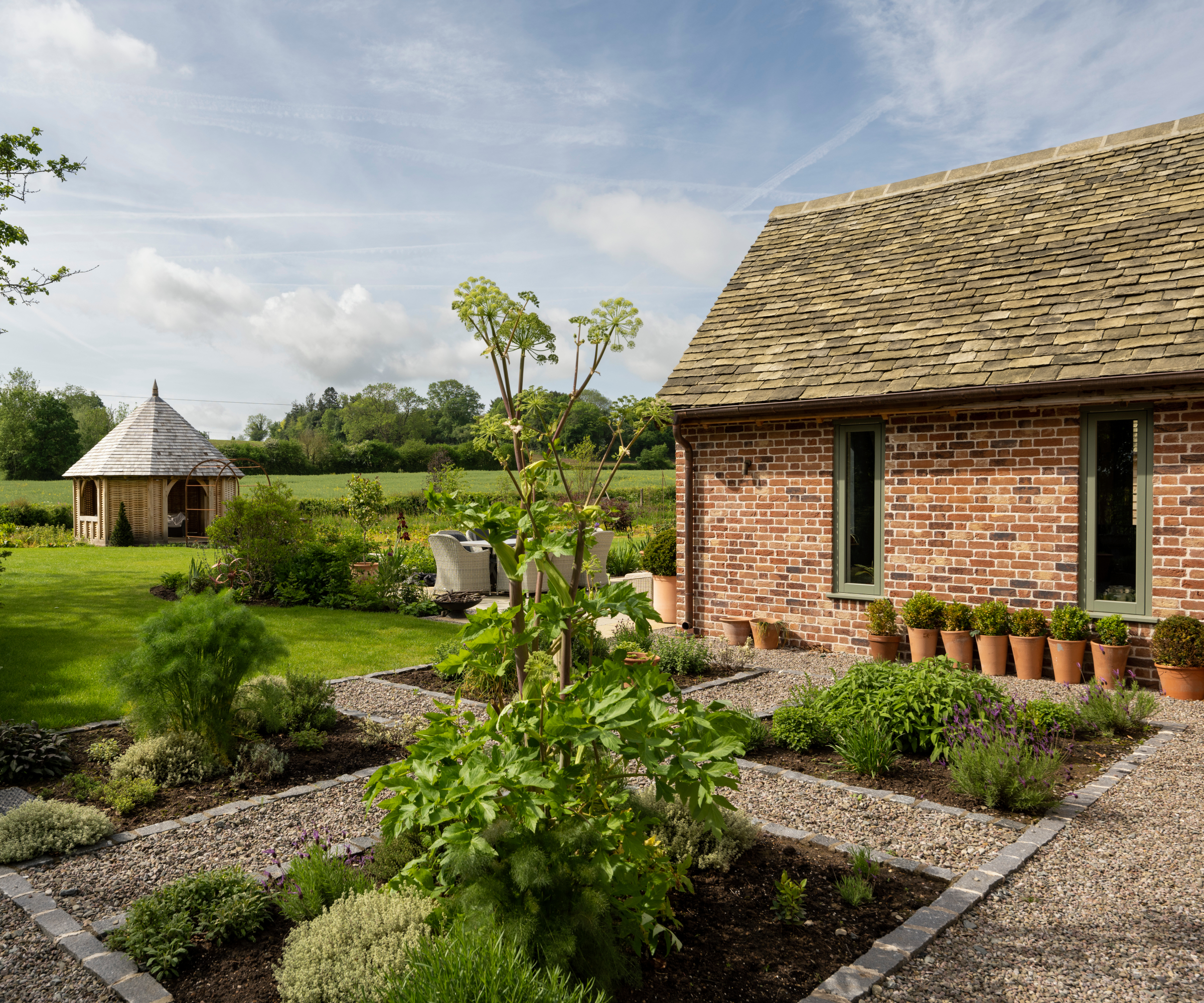 brick single storey house with planted beds in courtyard and natural hedging around the boundaries