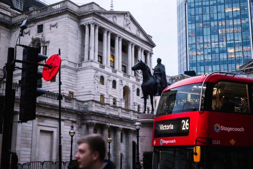 The facade of the Bank of England (BOE) in the City of London, UK, with a number 26 bus in the foreground.