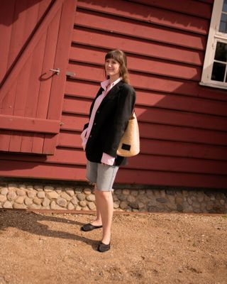 senior fashion editor Halie LeSavage wears a black blazer with a pink Saks Potts shirt and jean shorts and mesh flats at Copenhagen fashion week