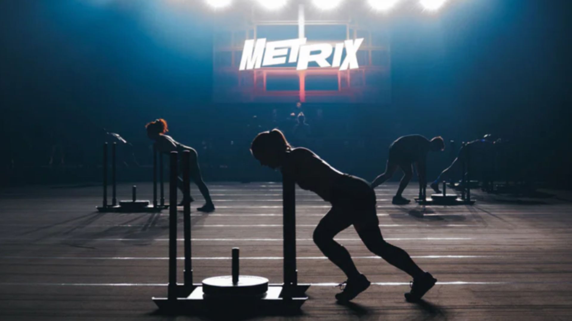 an image of a woman doing a sled push as part of METRIX fitness compeition