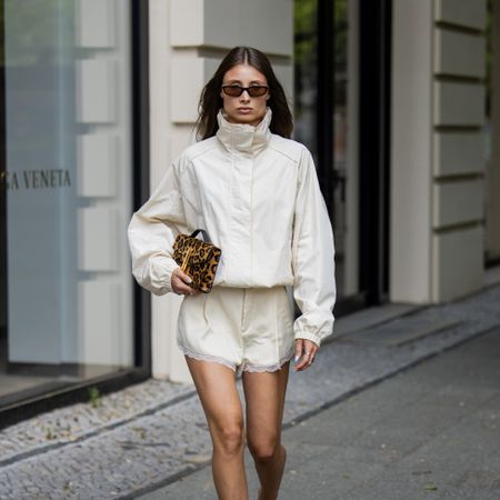 stylish woman wearing a cream funnel neck jacket and cream silk shorts