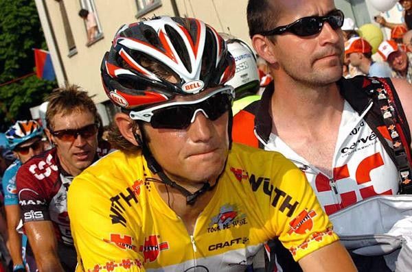Schleck is led to the podium by his team soigneur