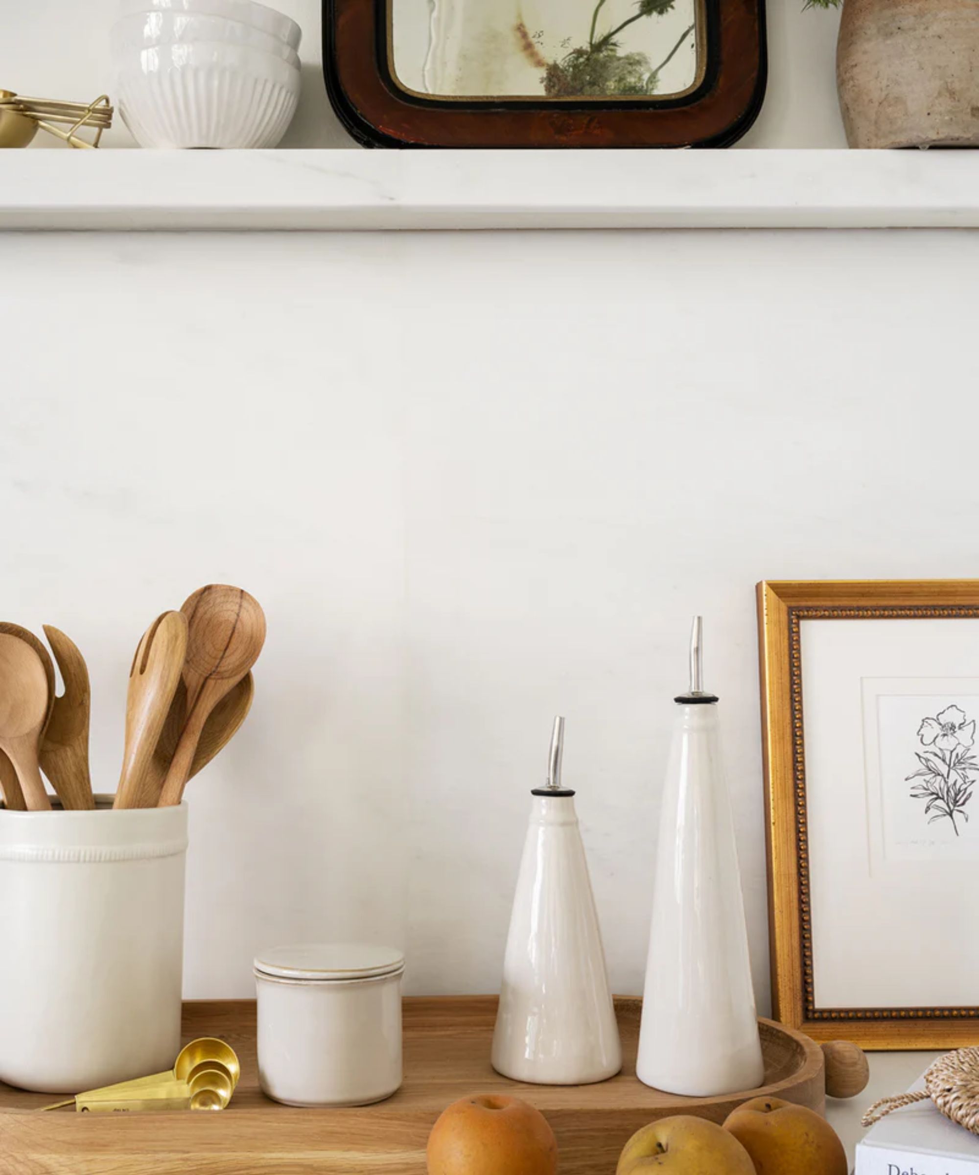 Kitchen counter with white ceramic oil cruets and crocks, plus wooden serving boards and utensils