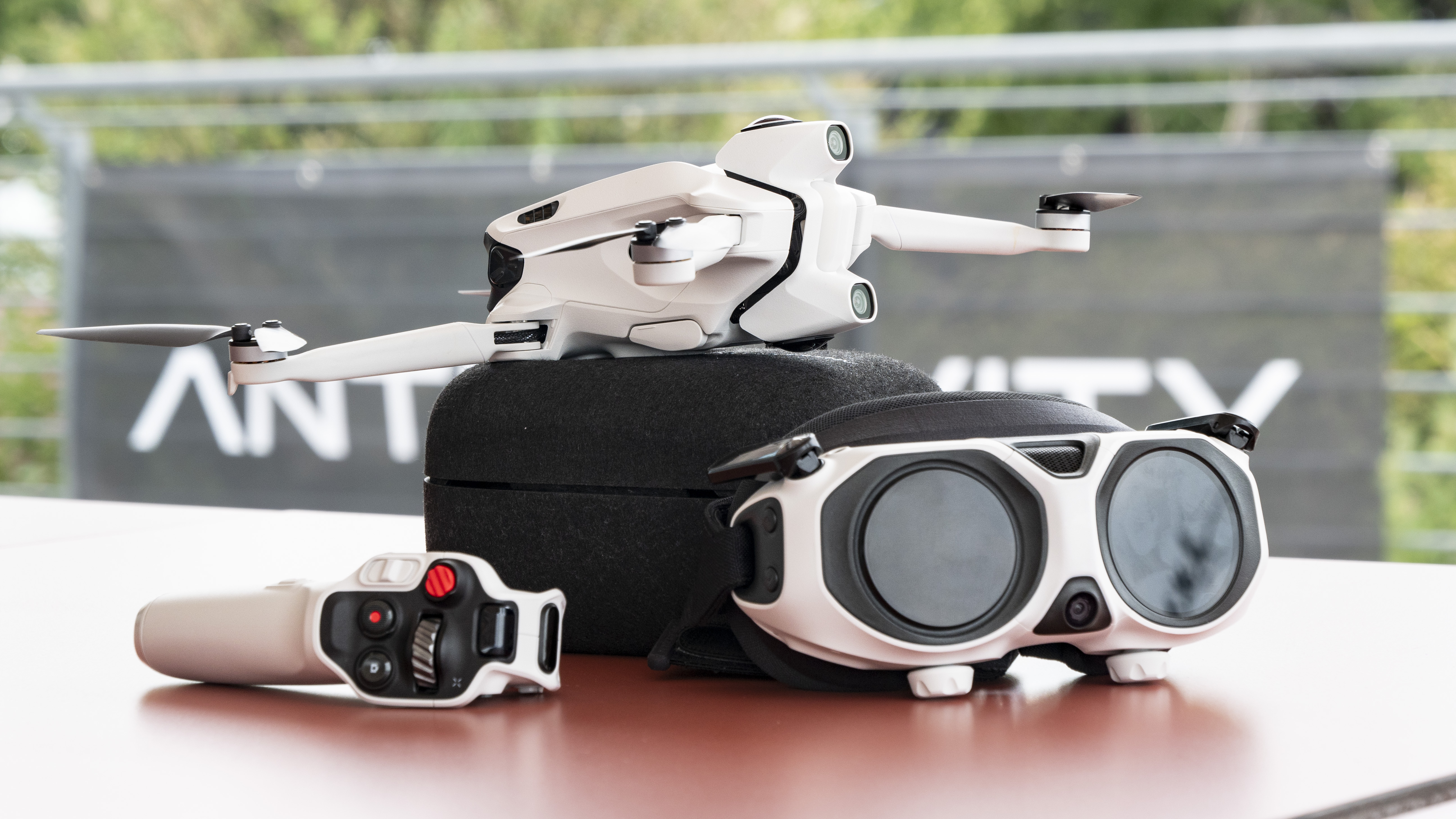 Antigravity A1 drone by Insta360 alongside its headset and controller, on a red table