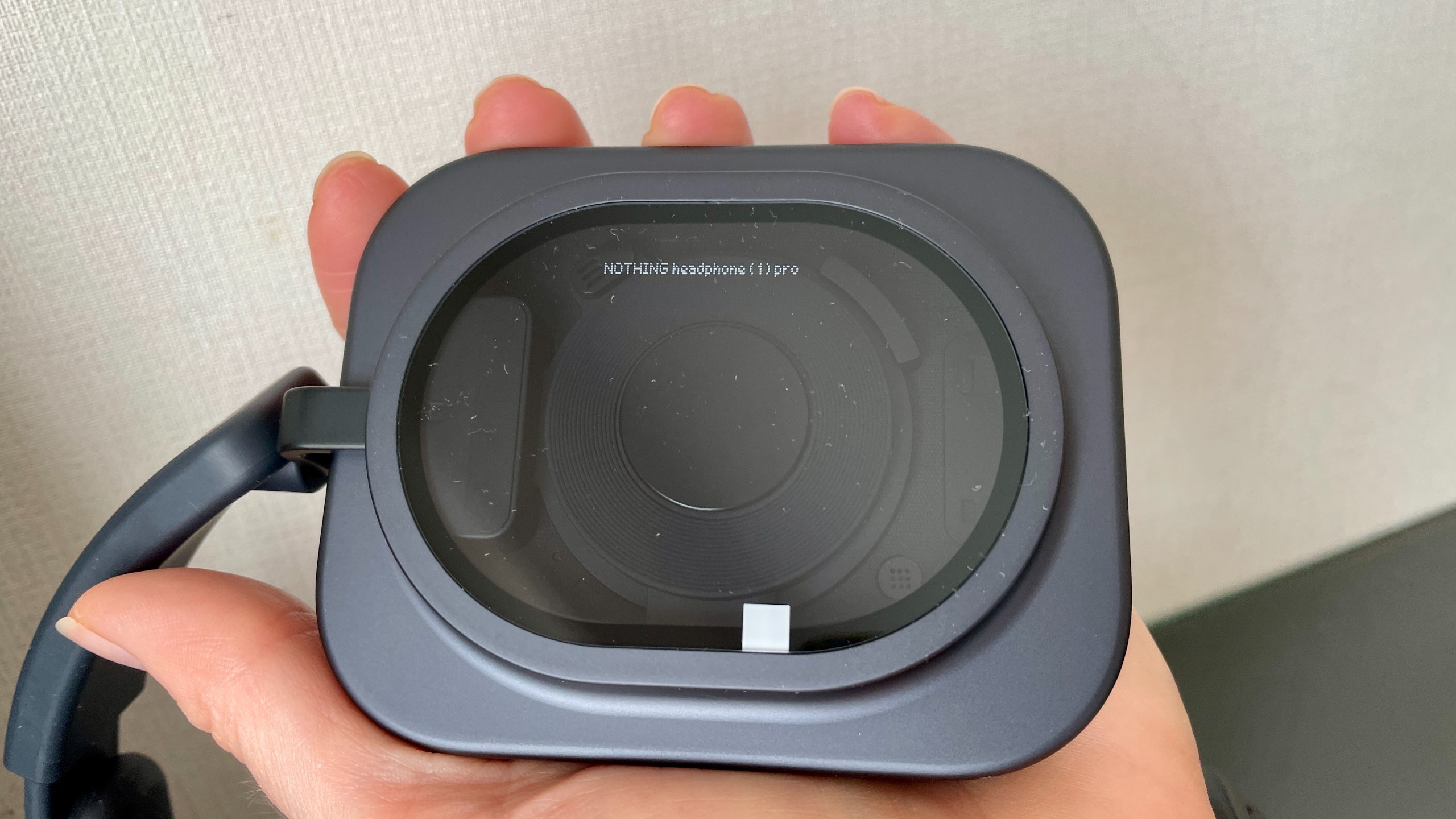 Nothing Headphone (1) Pro with the case on a shiny black and glass table, held in a hand