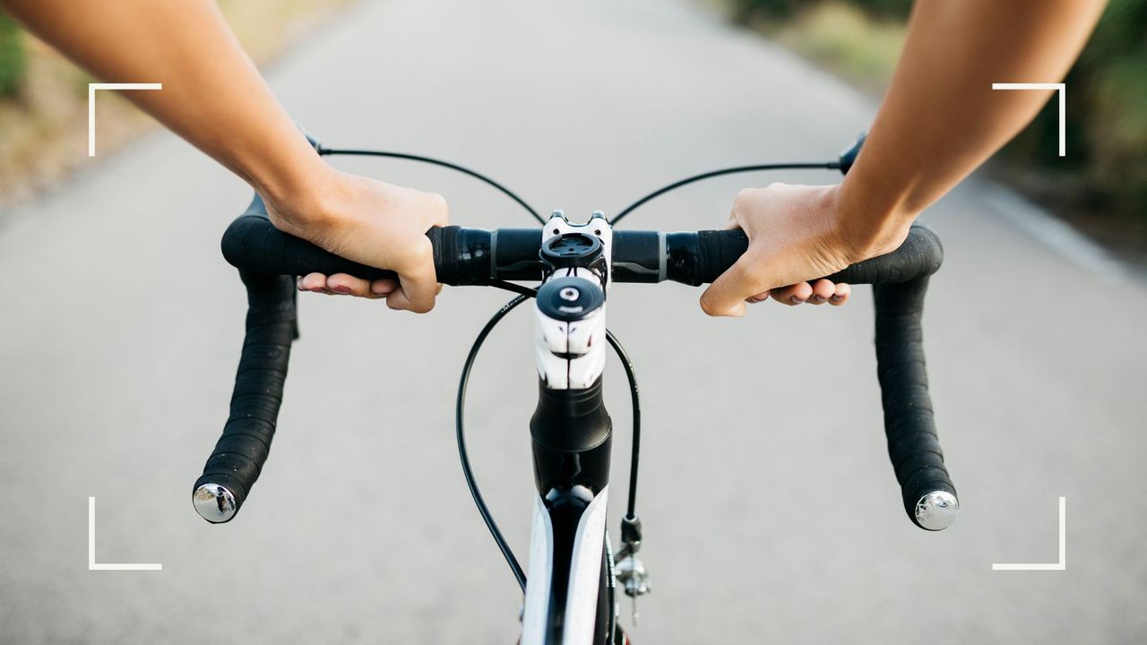 Woman holding bike handlebars, cycling along a gravel round after learning how often should you do cardio exercise