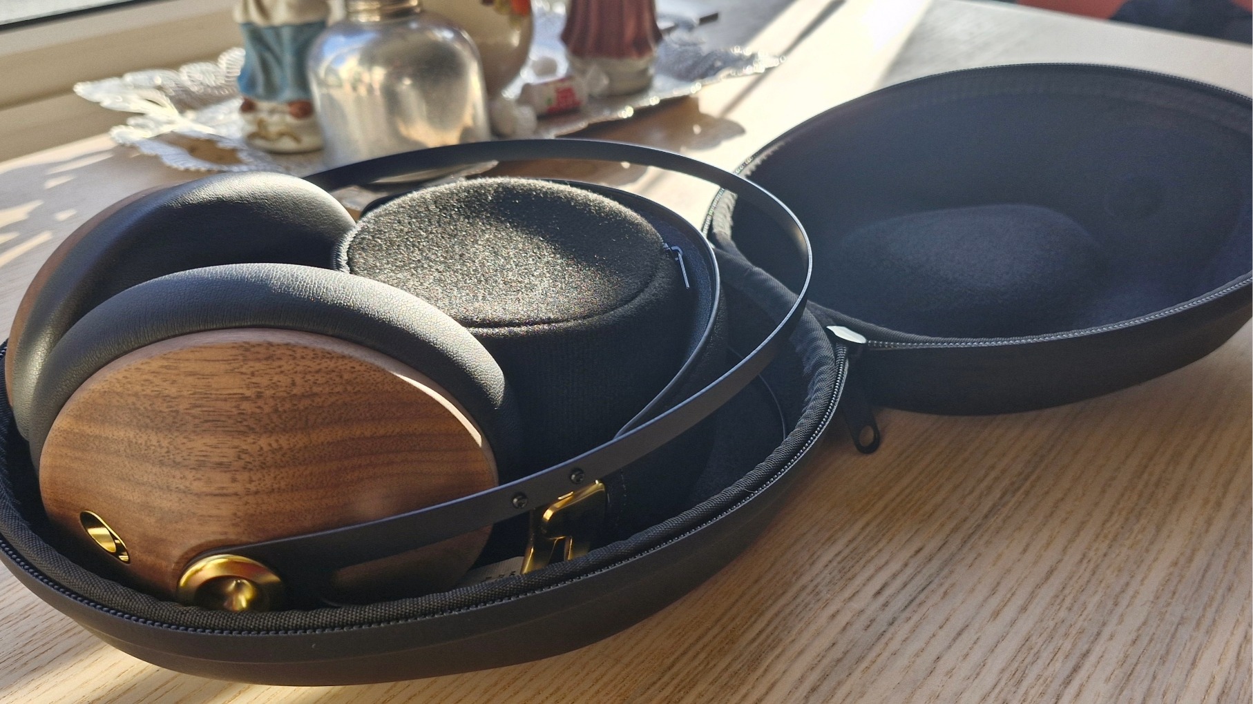 Meze Audio 99 Classics 2nd Gen over-ear headphones in their hard carry case, placed on a wooden table.
