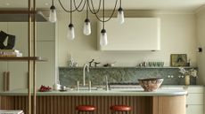 green kitchen with red bar stools and marble backsplash
