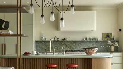 green kitchen with red bar stools and marble backsplash