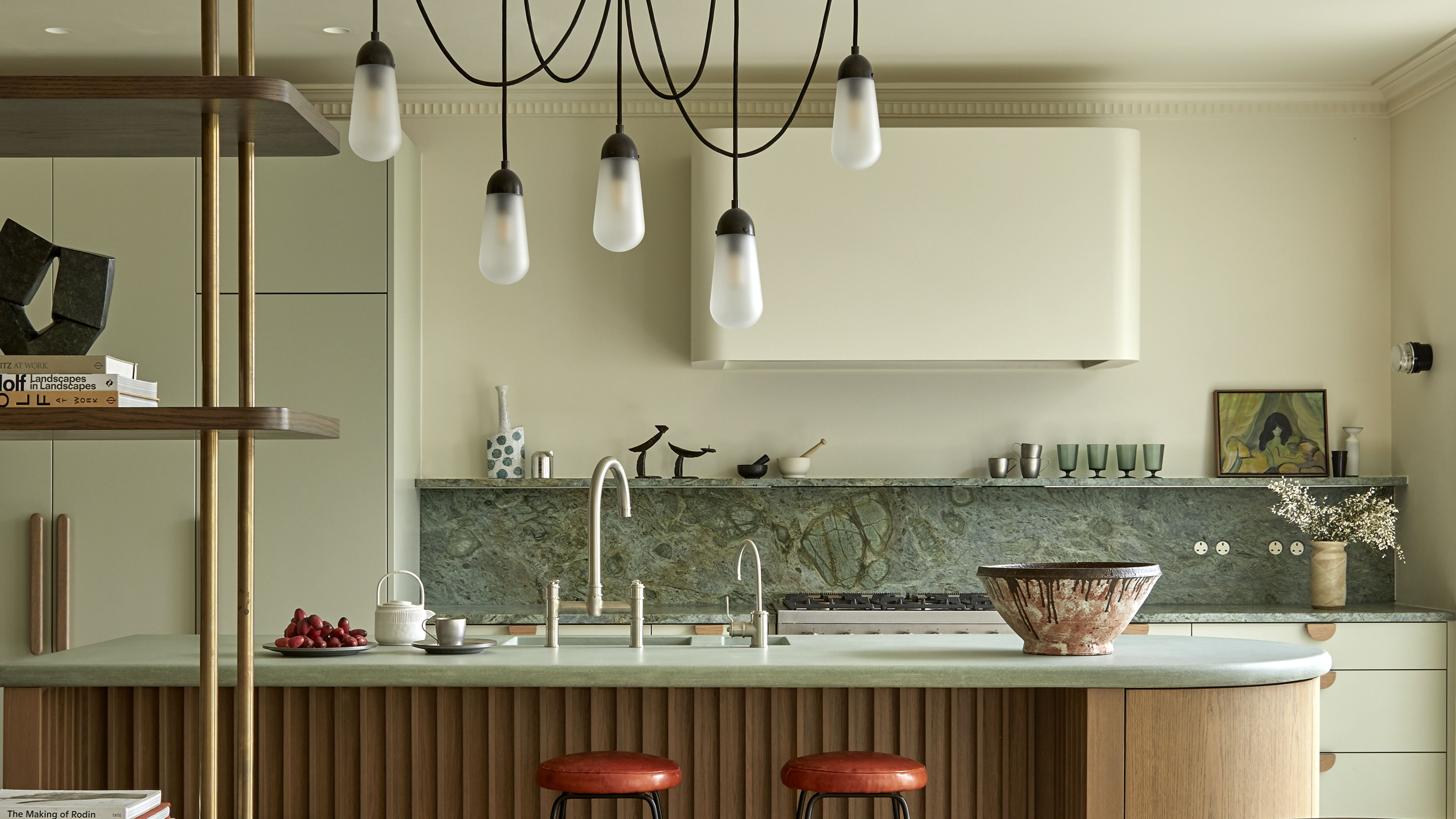 green kitchen with red bar stools and marble backsplash