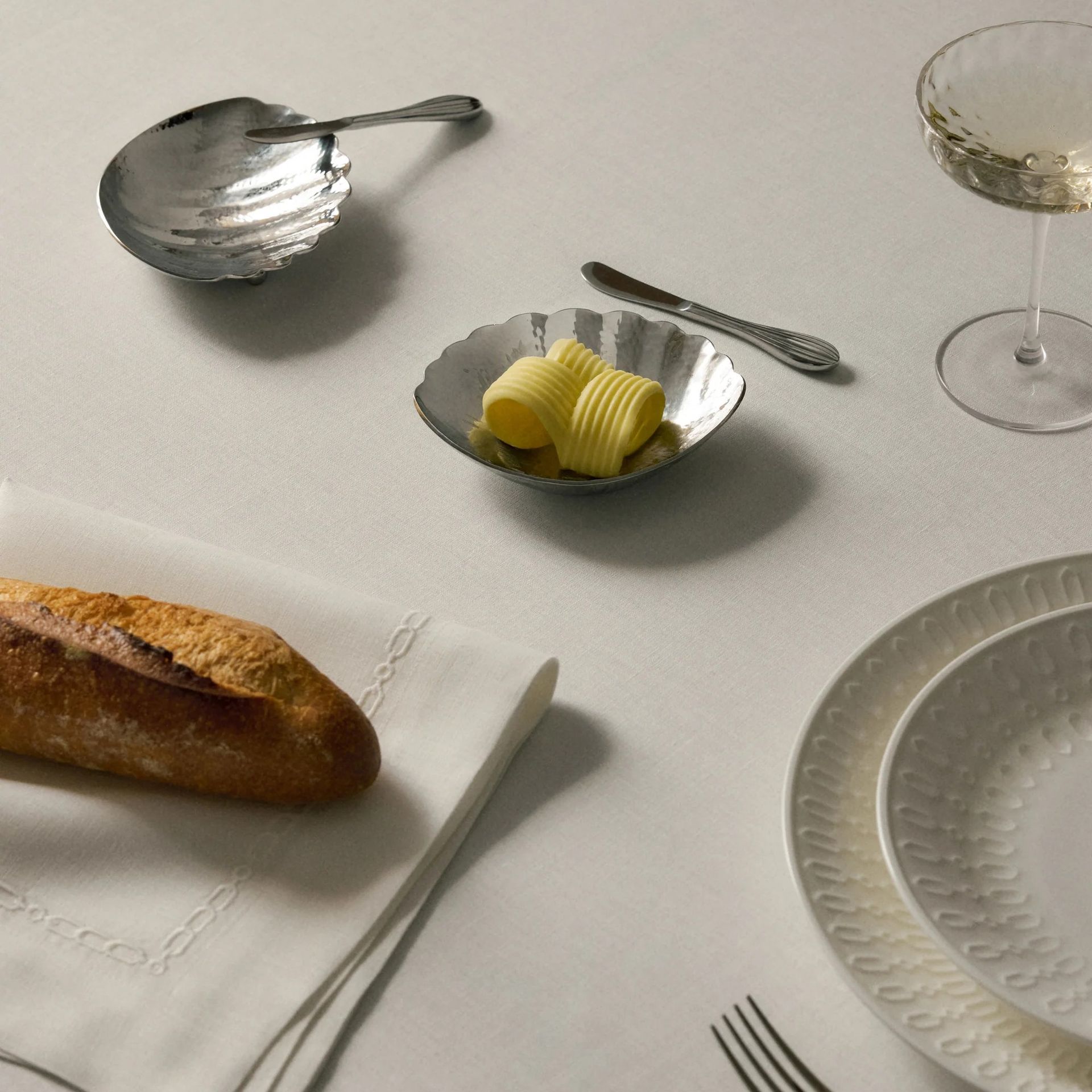 A dining table set with the Dover plates and Isla shell-shaped butter dishes from Victoria Beckham's tableware collection with Westwing