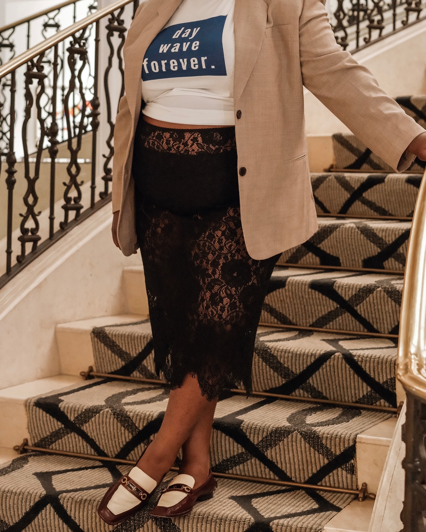 An image of @abimarvel wearing a linen blazer with a graphic white t-shirt, lace skirt and loafers.