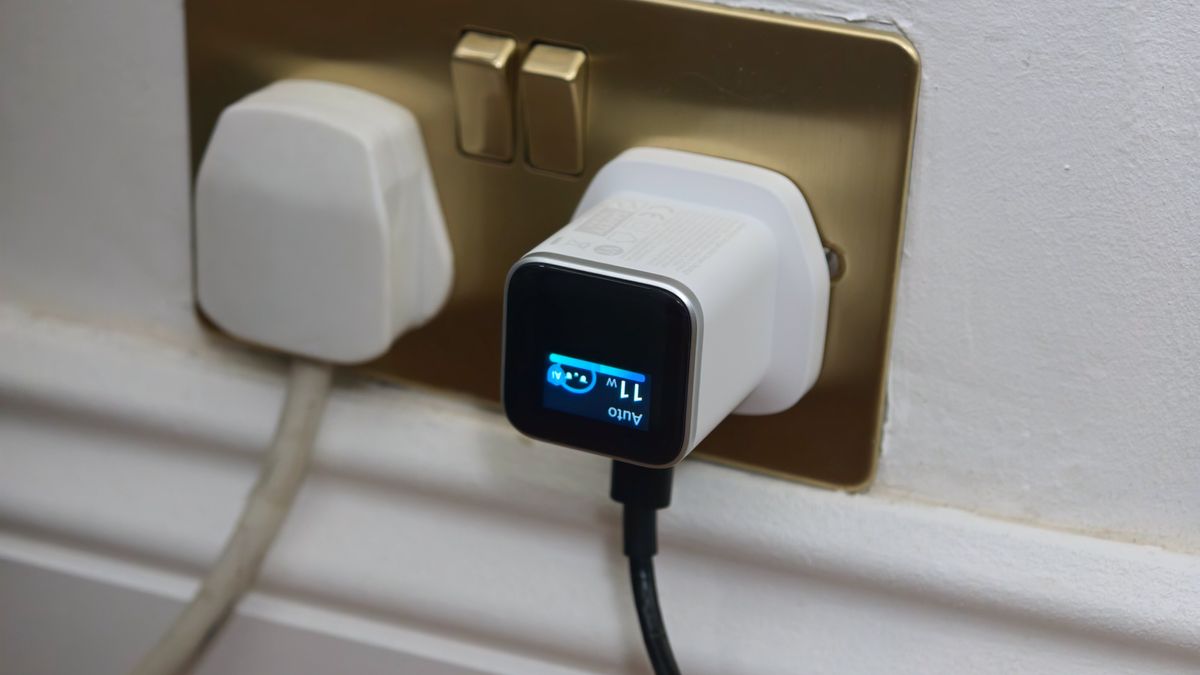 Anker Nano Charger plugged into a wall socket with its smart display rotated upside down.