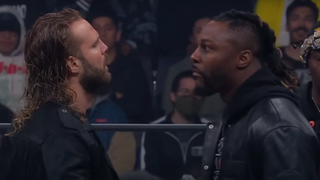 Hangman Page and Swerve Strickland stare each other down in the ring.
