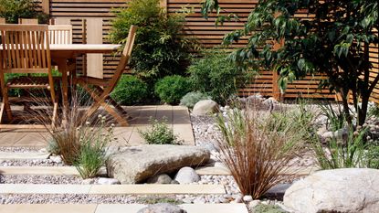 modern way of landscaping with boulders to edge a garden patio