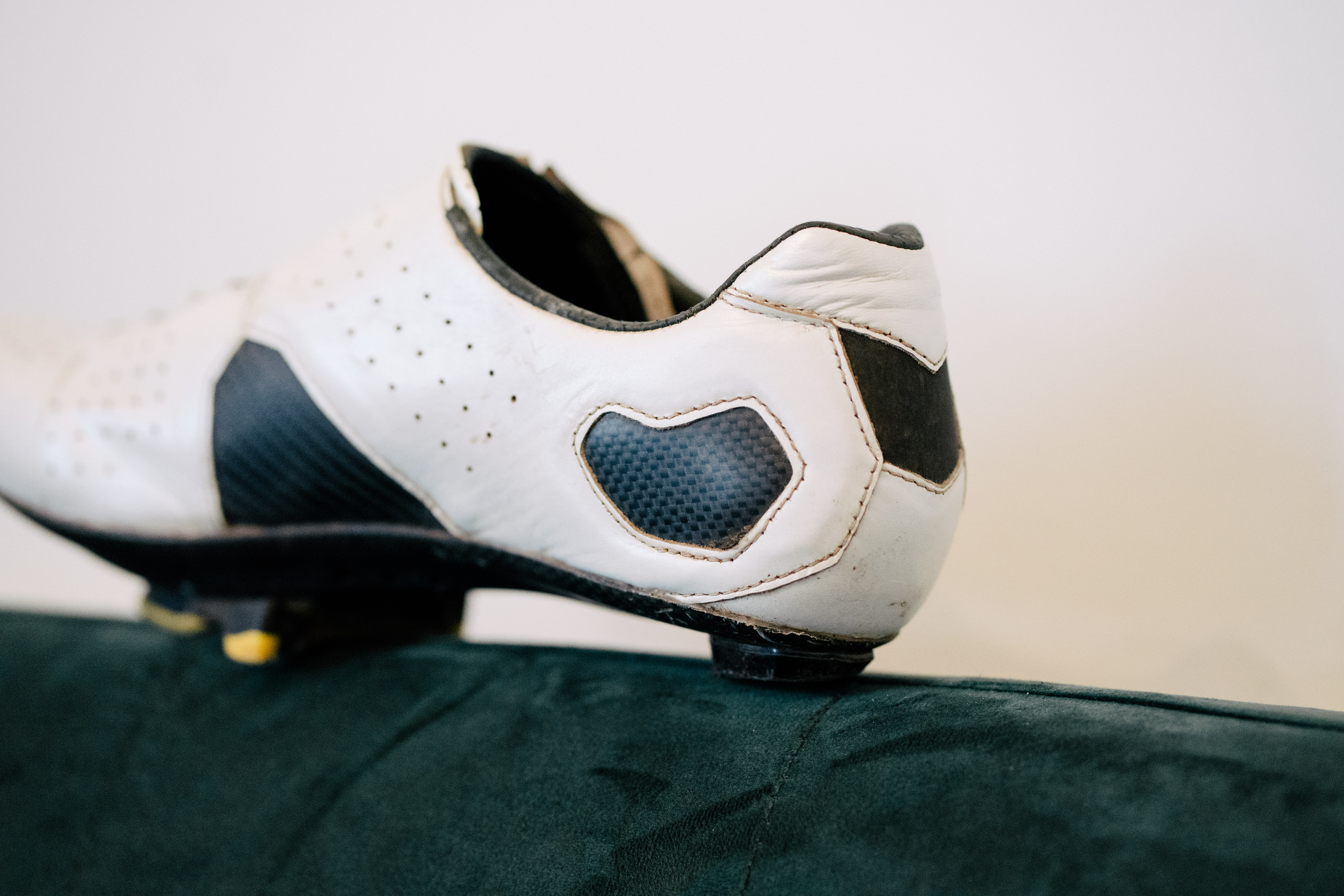 A white leather cycling shoe on a green sofa