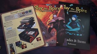 Slay the Spire the board game manuals on a playmat background