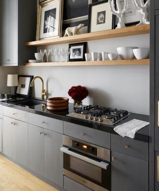 gray kitchen with beams, wooden floor, black countertops, hanging copper pans, open shelving, storage ideas, farmshouse style,