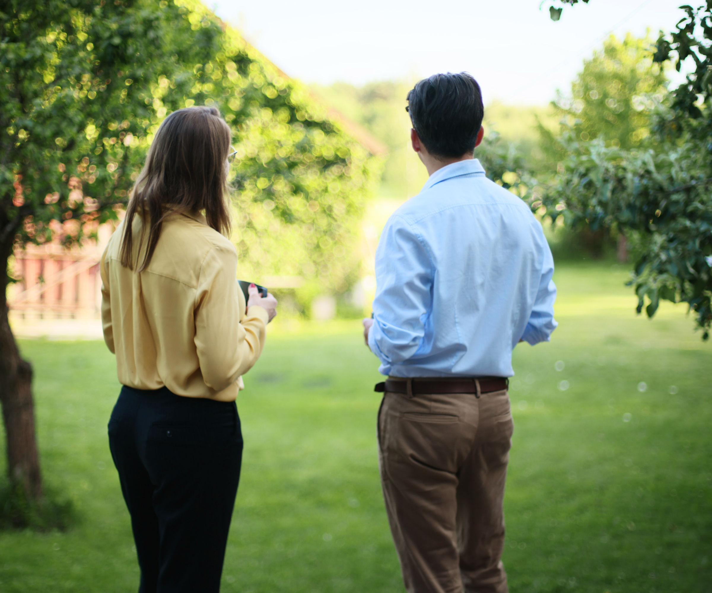 male and female stood looking at garden with lawn and trees