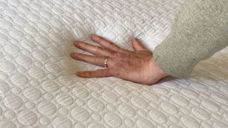 A hand pressing down on the Simba GO Hybrid mattress